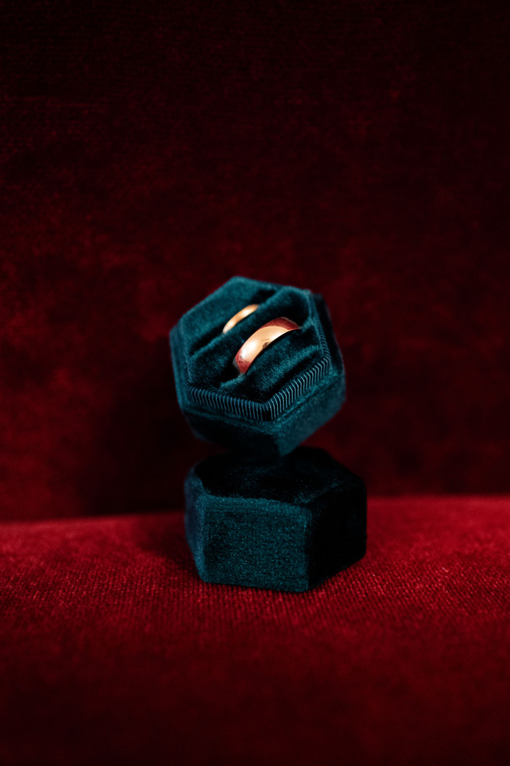 Alliances en or présentées dans un écrin en velours bleu sur un fond rouge.