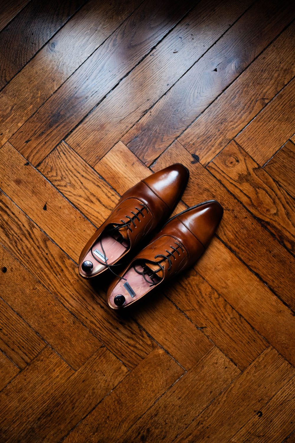 Paire de chaussures en cuir marron élégamment posées sur un parquet en bois.