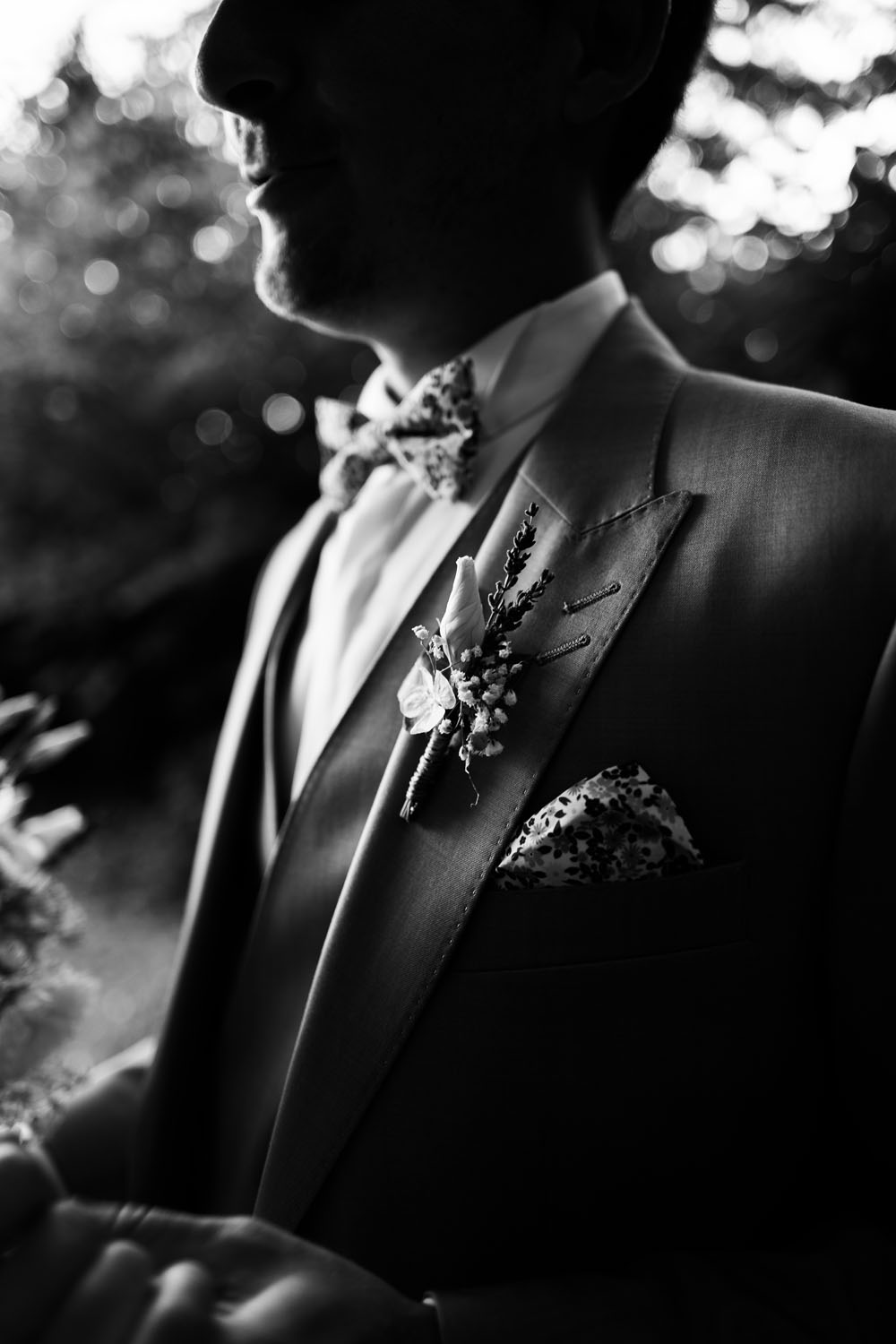 Détail du costume de mariage avec nœud papillon et fleur de boutonnière.