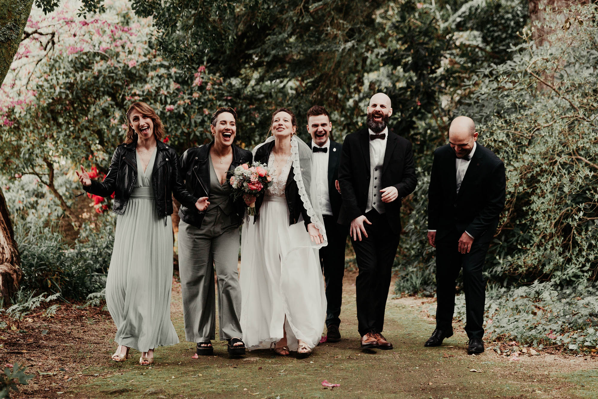 Groupe d’invités marchant ensemble lors d’un mariage en extérieur, vêtus de tenues formelles.