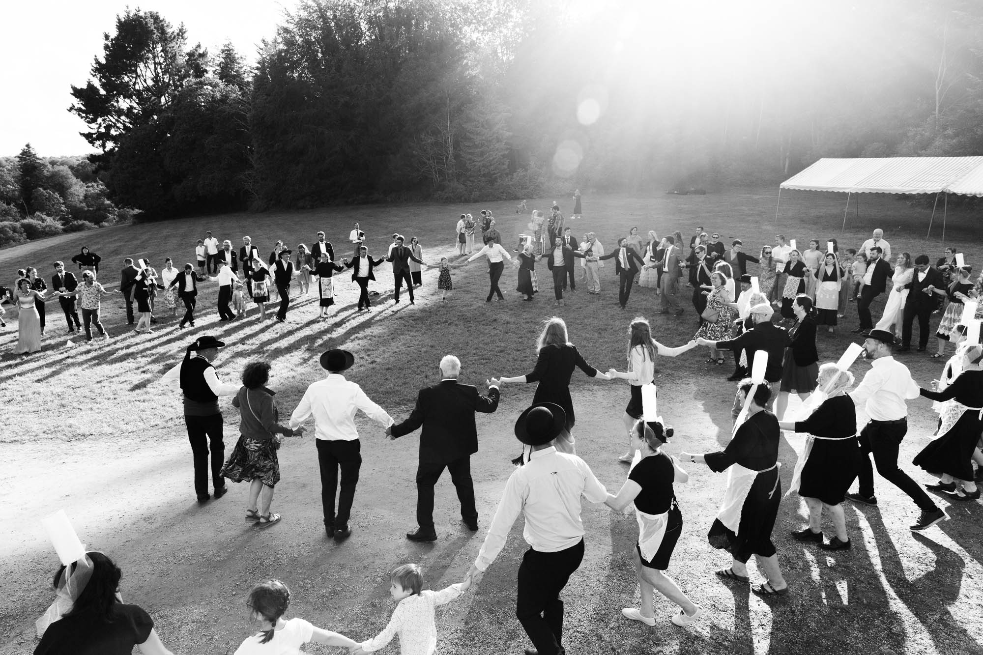 Invités de mariage en Bretagne formant une grande ronde en plein air sous un soleil éclatant.